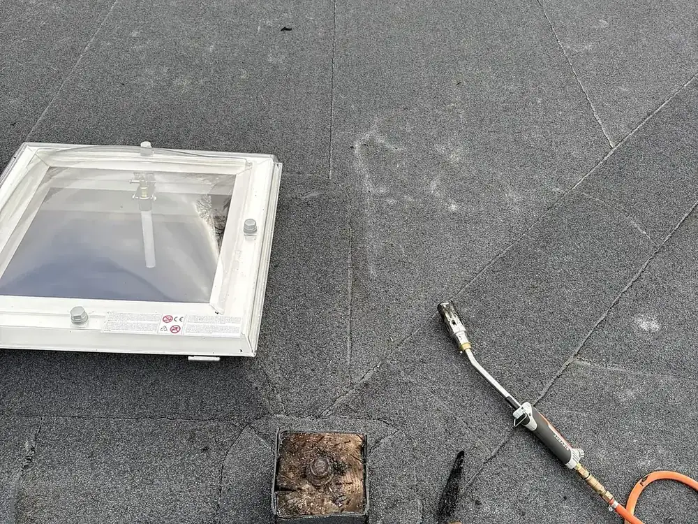 Bitumen plat dak met nieuwe lichtkoepel en dakdoorvoer