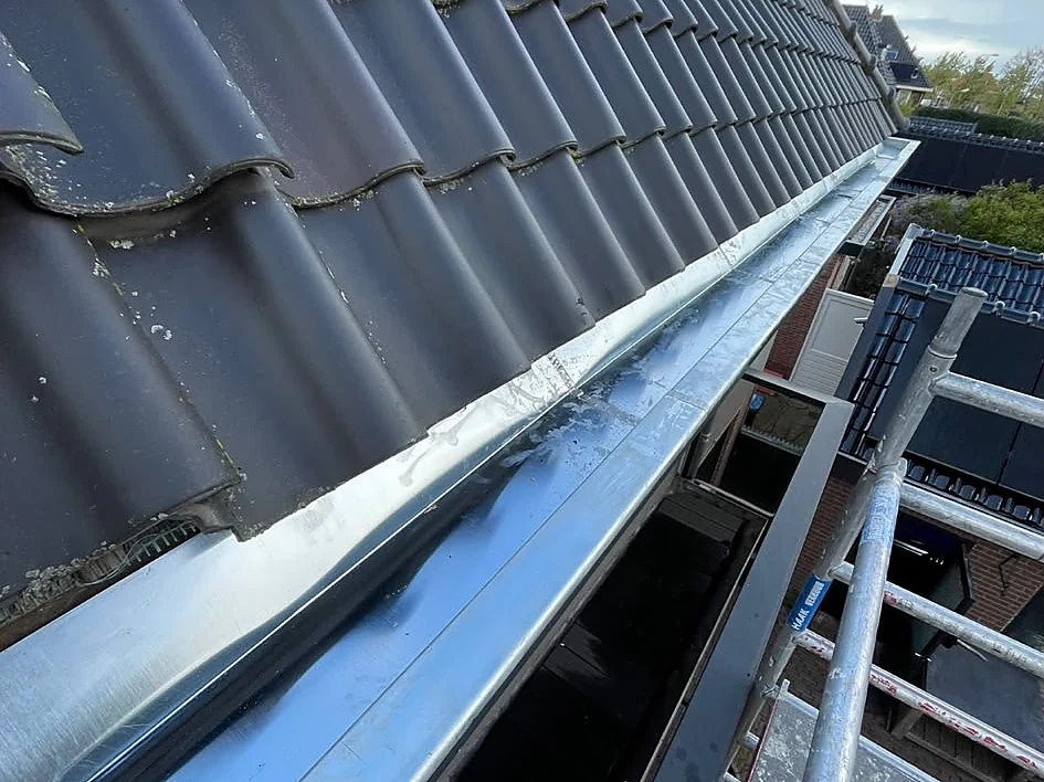 Nieuwe zinken mastgoot langs een pannendak